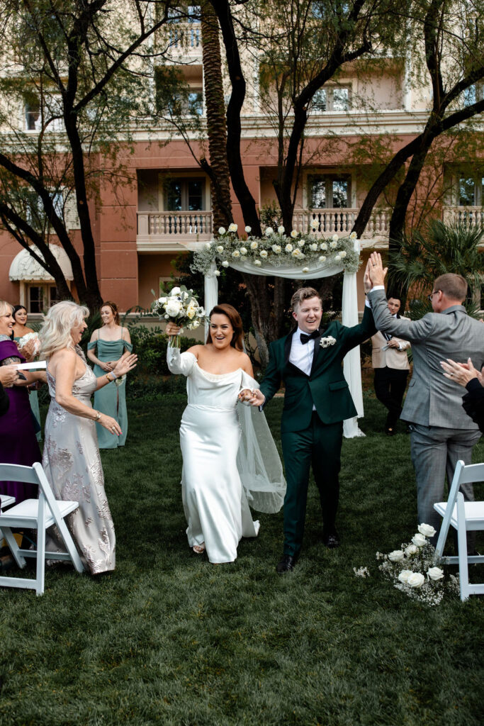 Bride and groom walking back down the aisle as husband and wife after their JW Marriott Las Vegas wedding ceremony on the lawn