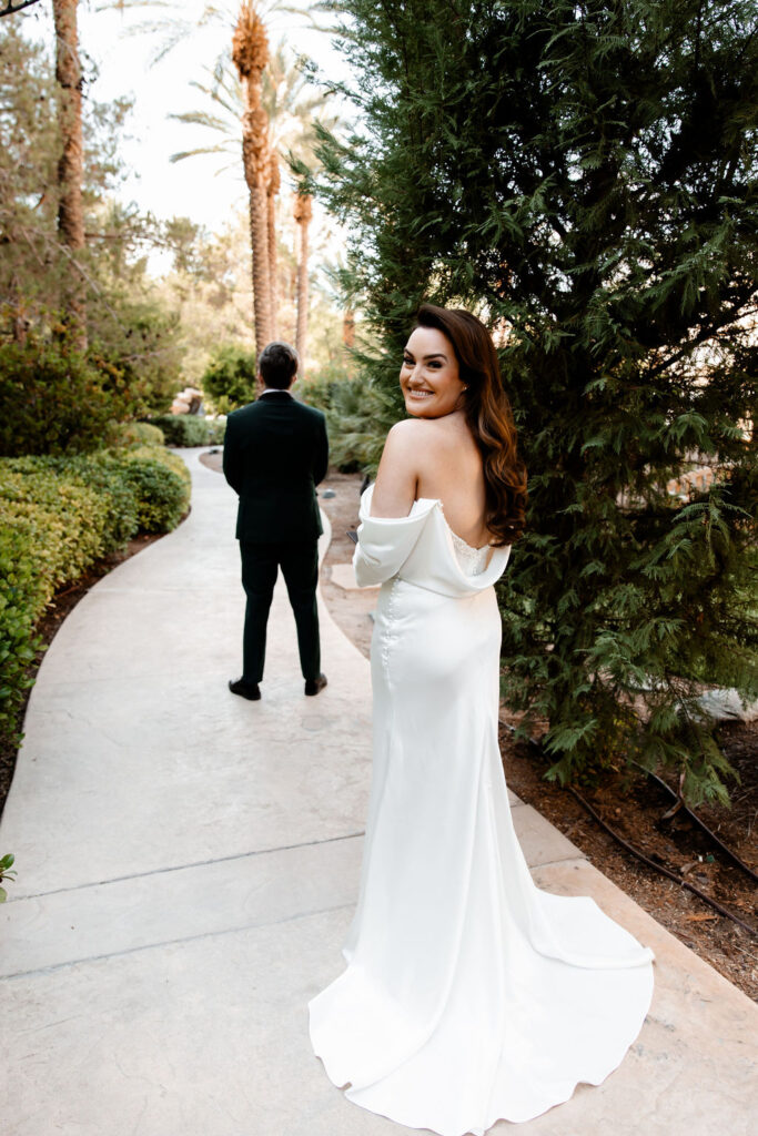 Bride looking back at the camera as she's about to share a first look with her groom at JW Marriott in Las Vegas