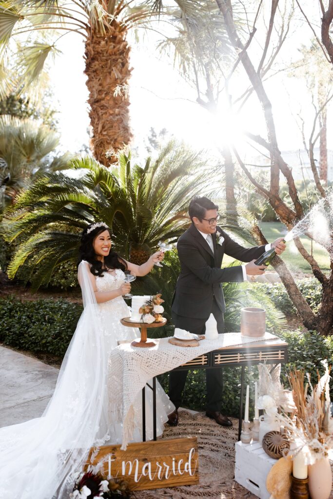Bride and groom popping champagne after their JW Marriott Las Vegas elopement