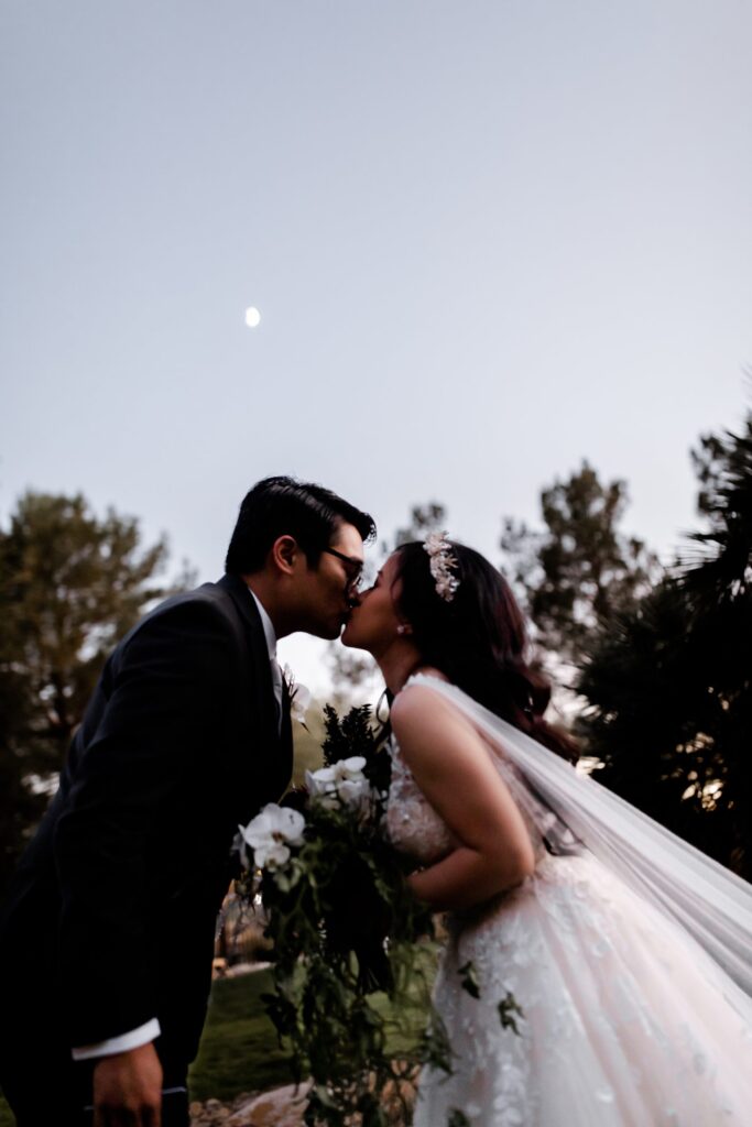 Bride and groom kissing with the moon in the background