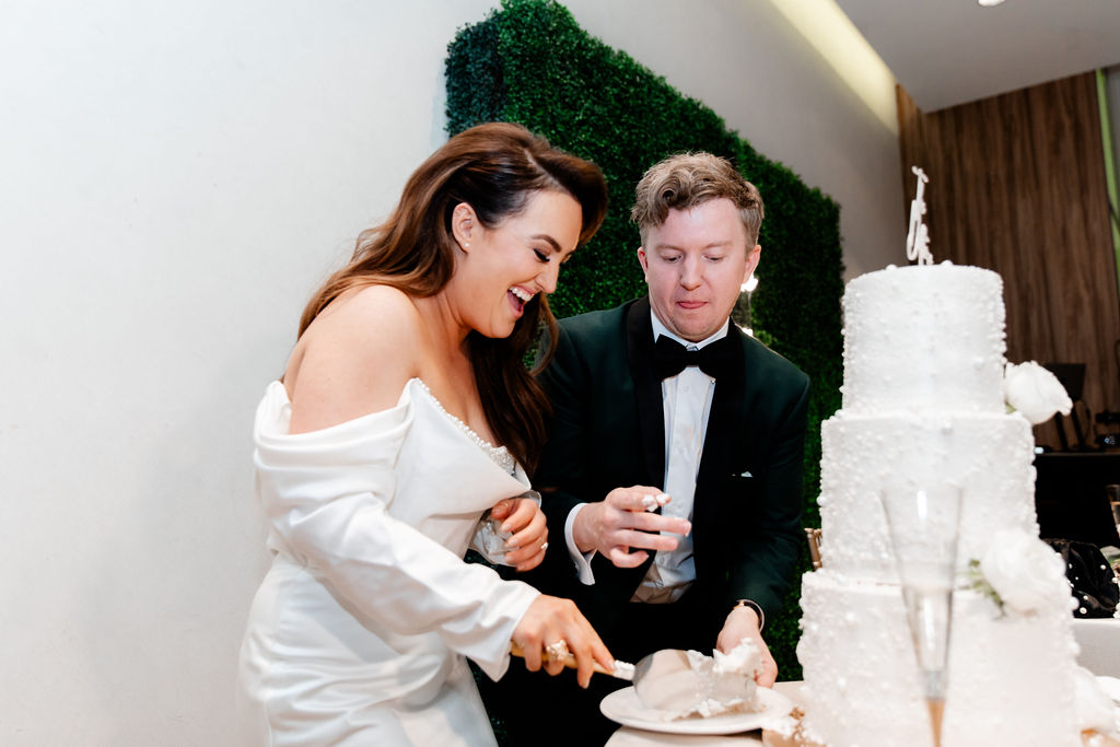 Bride and groom cutting into their three tiered wedding cake