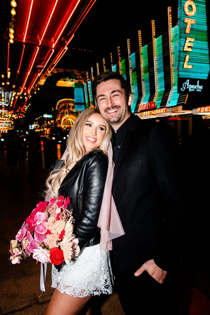 Bride and groom posing for night Vegas elopement photos on Fremont Street