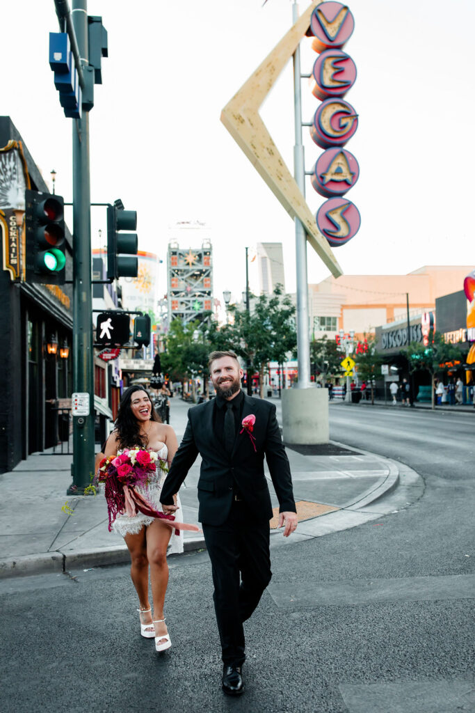 Bride and groom holding hands and walking across the road on Fremont Street